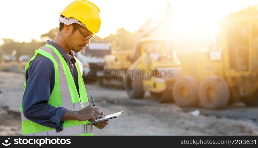 Asian engineer with hardhat using tablet pc computer inspecting and working at construction site