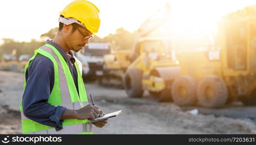 Asian engineer with hardhat using tablet pc computer inspecting and working at construction site