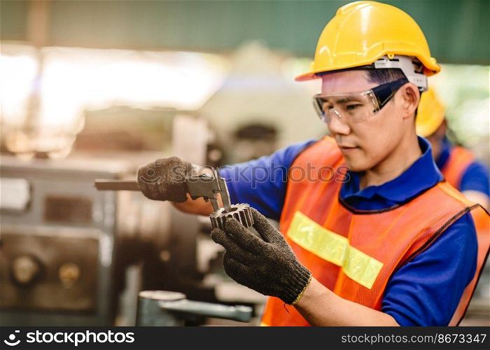 Asian engineer worker using Vernier Caliper to check size for accuracy precision quality control of service machine in factory.