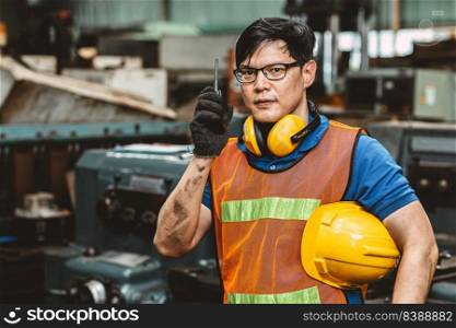 Asian engineer worker with protection suit set hard working in factory handle communication radio looking camera and smile.