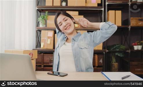 Asian entrepreneur business woman stretching her body after answer customer question, Female owner of SME online relax after working at home. Small business owner at home office concept.