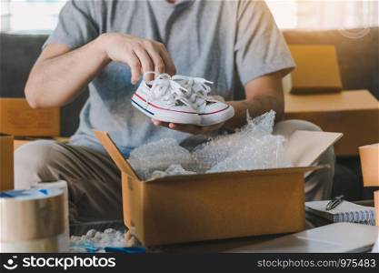 Asian entrepreneur teenager is carrying baby shoes and put in a cardboard box customer to deliver the product at home.