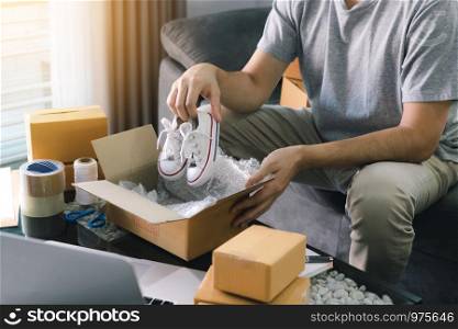 Asian entrepreneur teenager is carrying baby shoes and put in a cardboard box customer to deliver the product at home.