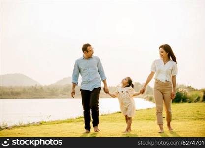 Asian family and daughter running and holding hands in a beautiful park, with a sunny sky and a feeling of love and happiness, Happy Family Day Concept