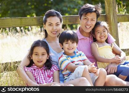 Asian Family Relaxing By Gate On Walk In Countryside