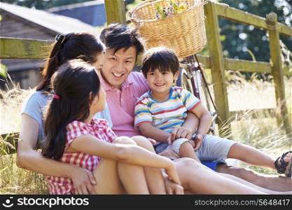 Asian Family Resting By Fence With Old Fashioned Cycle