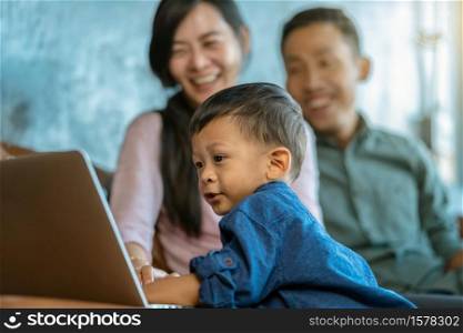 Asian family with son are looking the cartoon via technology laptop and playing together when living in loft house for Self learning or home school,Family home school concept
