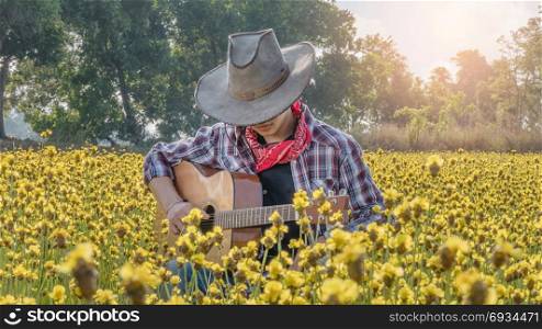 Asian farmer with guitar. Asian farmer sitting in his bright yellow field with guitar