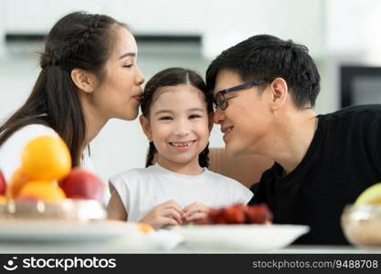 Asian father and mother Show your love to little daughter and having breakfast together happily in the dining room of the house.