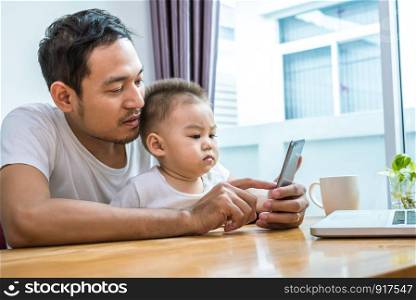 Asian father and son using smart phone together in home background. Technology and People concept. Lifestyles and Happy family theme. Internet and communication theme