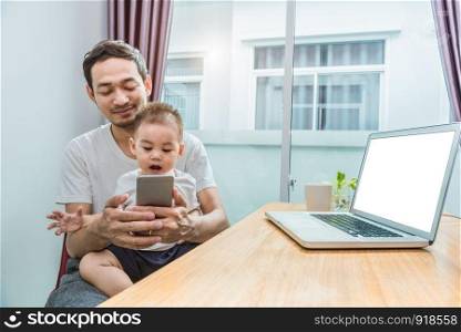 Asian father and son using smart phone together in home background. Technology and People concept. Lifestyles and Happy family theme. Internet and communication theme