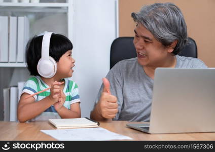 Asian father is work at the home with a daughter and studying online learning from school together. New lifestyle normal during a quarantine. Concept of stay home, freelance and fatherhood concept