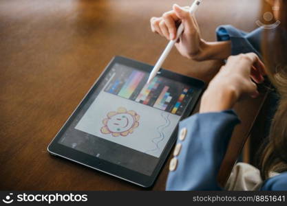 Asian female artist illustrator painting drawing on touch pad digital tablet with stylus pen, Lifestyle creative hobby woman digital artist draws a digital picture on digital tablet at cafe shop