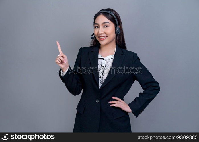 Asian female call center operator with happy smile face advertises job opportunity on empty space, wearing formal suit and headset on customizable isolated background for job recruitment. Jubilant. Attractive Asian operator with formal suit and headset. Jubilant