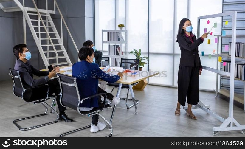 asian female coach Wear protective mask speaker make flip chart presentation to diverse business people meeting with diverse genders (LGBT) in the room at office,COVID-19