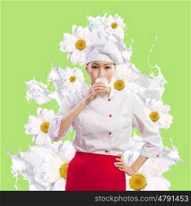 Asian female cook against milk splashes. Asian female cook against milk splashes in red apron against flower background drinking milk