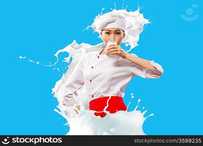 Asian female cook against milk splashes in red apron against color background drinking milk