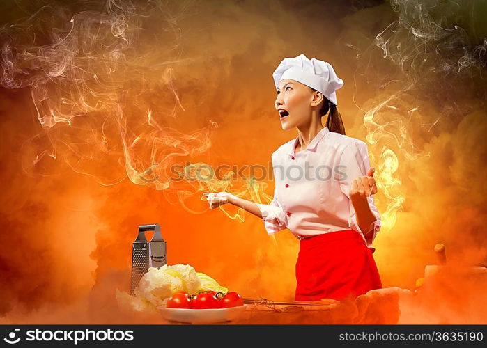 Asian female cook in anger against color background with shine effects