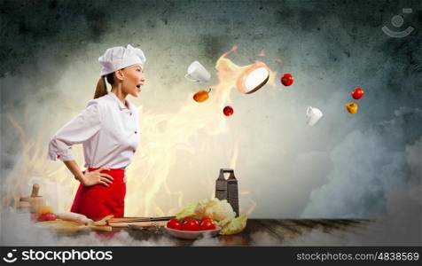 Asian female cook in anger. Asian female cook in anger with flyung vegetables against color background with shine effects