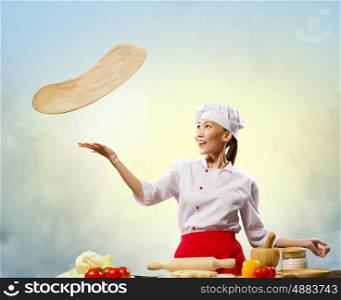 Asian female cook making pizza. Asian female cook making pizza standing against color background