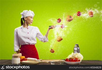 Asian female cook with knife. Asian female cook with knife cutting fruits and vegetables in air