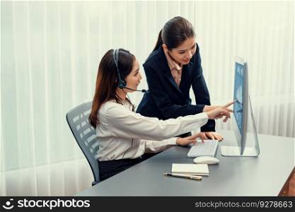 Asian female customer support operator wearing headset is guided by her supportive manager. Experienced colleague help operator handle a call with a client, providing advice and guidance. Enthusiastic. Asian female customer support operator guided by manger Enthusiastic
