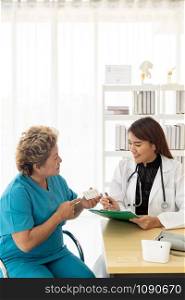 Asian female doctor talking prescribing pills to old senior elderly patient in examination room of clinic hospital.