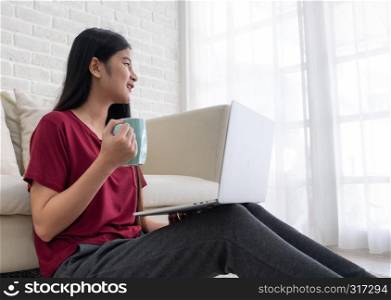 Asian female freelancer smile and drink coffee with relax emotion and looking out of window at home.working online lifestyle
