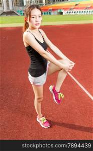 Asian female jogger stretching legs on sports field for warm up