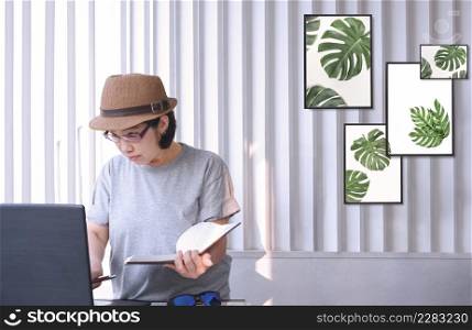 Asian female middle aged hipster designer in vintage clothes using laptop computer while working in home office room, 90s fashion style