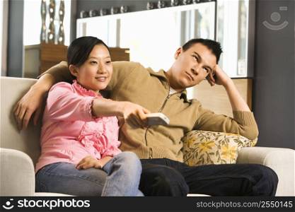 Asian female pointing remote while Asian male looks annoyed.