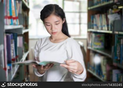 Asian female students holding for selection Book in library