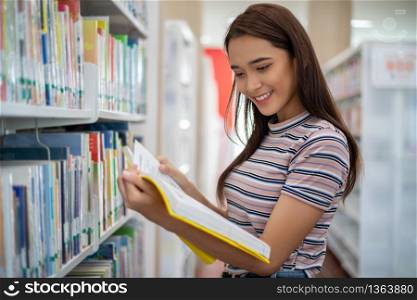 Asian female students smiling and reading Book in library