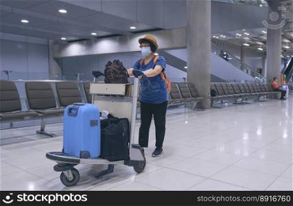 Asian female tourist wearing face masks with luggage walking in airport terminal, full length and perspective side view