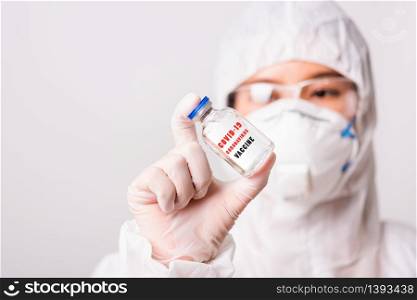 "Asian female woman doctor or nurse in PPE uniform and gloves wearing face mask protective in laboratory holding medicine vial coronavirus vaccine bottle and on bottle has "COVID-19 VACCINE" text label"