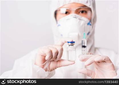 Asian female woman doctor or nurse in PPE uniform and gloves wearing face mask protective in the laboratory holding needle syringe drug and medicine vial vaccine bottle, Health medical concept