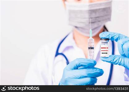"Asian female woman doctor or nurse in uniform and gloves wearing face mask protective in lab hold needle syringe drug and medicine vial vaccine bottle and on bottle has "COVID-19 VACCINE" text label"