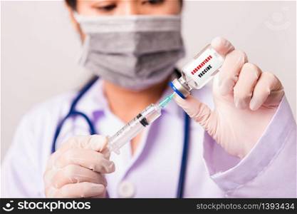 "Asian female woman doctor or nurse in uniform and gloves wearing face mask protective in lab hold needle syringe drug and medicine vial vaccine bottle and on bottle has "COVID-19 VACCINE" text label"