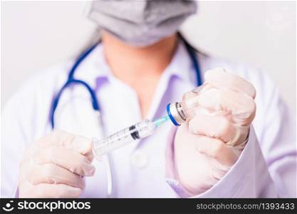 Asian female woman doctor or nurse in uniform and gloves with stethoscope wearing face mask protective in the laboratory holding syringe and medicine vial vaccine bottle, Health medical concepts