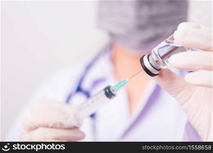 Asian female woman doctor or nurse in uniform and gloves with stethoscope wearing face mask protective in the laboratory holding syringe and medicine vial vaccine bottle, Health medical concepts
