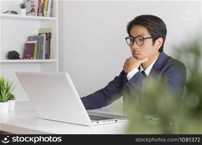 Asian Financial Advisor or Asian Consulting Businessman Analyze Financial Information in front of Laptop. Asian financial advisor or Asian consulting businessman working in office