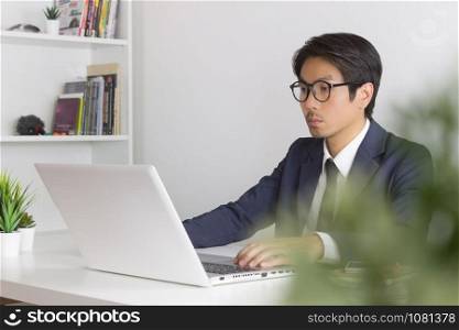 Asian Financial Advisor or Asian Consulting Businessman Seriously Working in front of Laptop. Asian financial advisor or Asian consulting businessman working in office