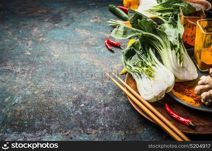 Asian food and eating concept: Chinese or Thai cuisine, cooking ingredients with pak choi and chopsticks on dark vintage background, place for text