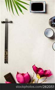 Asian food background - sake and chopsticks on a slate board over grey concrete background. Top view, flat lay. Asian food background, top view, flat lay