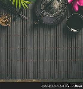 Asian food background - tea and chopsticks on dark rustic background. Top view, flat lay. Asian food background, tea and chopsticks on dark background.
