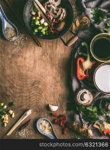 Asian food background with wok , coconut milk, soy sauce, sesame oil, chopped spices and vegetables on rustic wooden background. Asian eating and cooking ingredients, Chinese or Thai cuisine concept