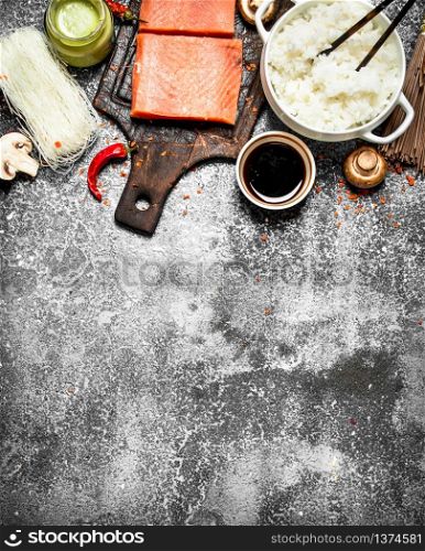 Asian food. Boiled rice with a piece of salmon and a variety of ingredients. On rustic background . Japanese table food.. Asian food. Boiled rice with a piece of salmon and a variety of ingredients. On rustic background .