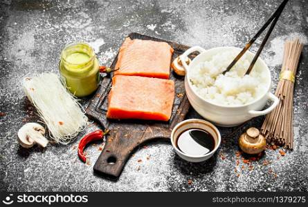 Asian food. Boiled rice with a piece of salmon and a variety of ingredients. On rustic background . Japanese table food.. Asian food. Boiled rice with a piece of salmon and a variety of ingredients. On rustic background .