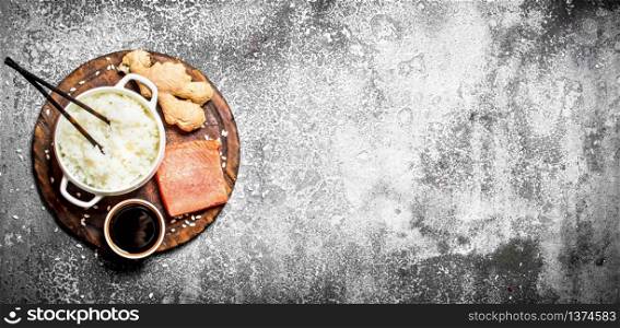 Asian food. Boiled rice with a piece of salmon and soy sauce. On rustic background . Japanese cuisine table.. Asian food. Boiled rice with a piece of salmon and soy sauce. On rustic background .