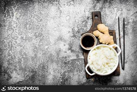 Asian food. Boiled rice with soy sauce on the old Board. On rustic background. Japanese cuisine table.. Asian food. Boiled rice with soy sauce on the old Board. On rustic background.
